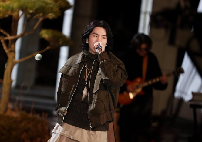 coat microphone guitar person jacket performer solo performance necklace face concert